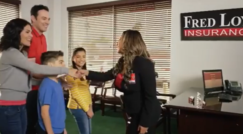 Fred Loya Insurance agent shaking hands with a family of four inside a local office, showcasing friendly customer service.